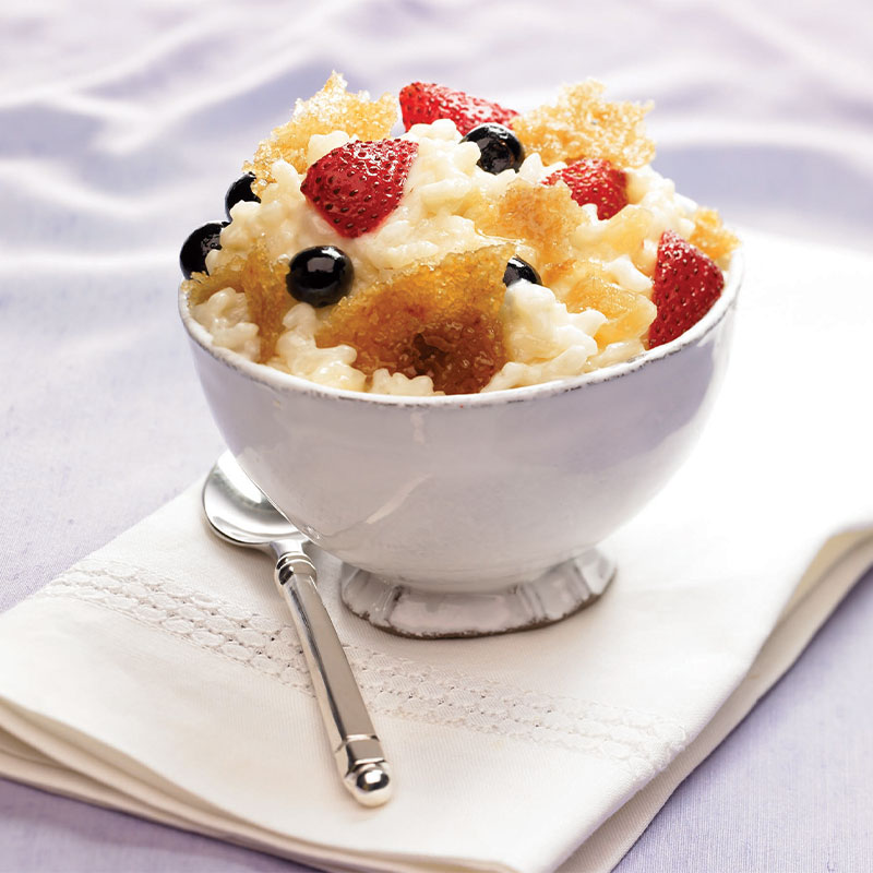 Creamy Rice Pudding Brulee with Gingered Berries in a white dish.
