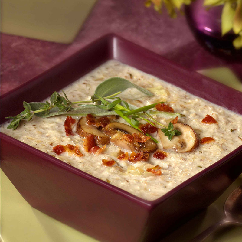 Overhead shot of Cremini Mushroom and Roasted Garlic Rice Soup in a maroon bowl. 