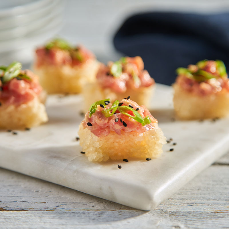 Crispy Rice & Tuna Canape Five Crispy Rice & Tuna Canape squares on a marble platter.