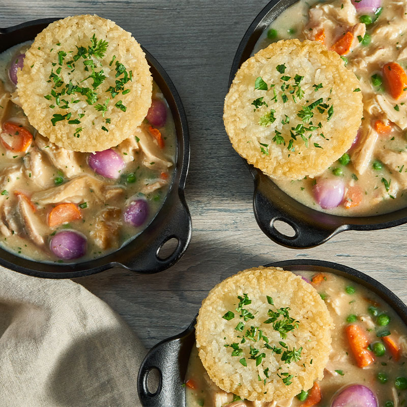 Overhead shot of three Chicken Pot Pies with a Crispy Rice Cake on top.  