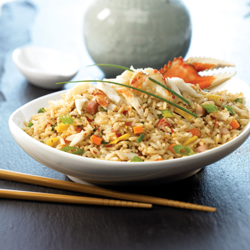 Side view of Dungeness crab fried rice in a white bowl.
