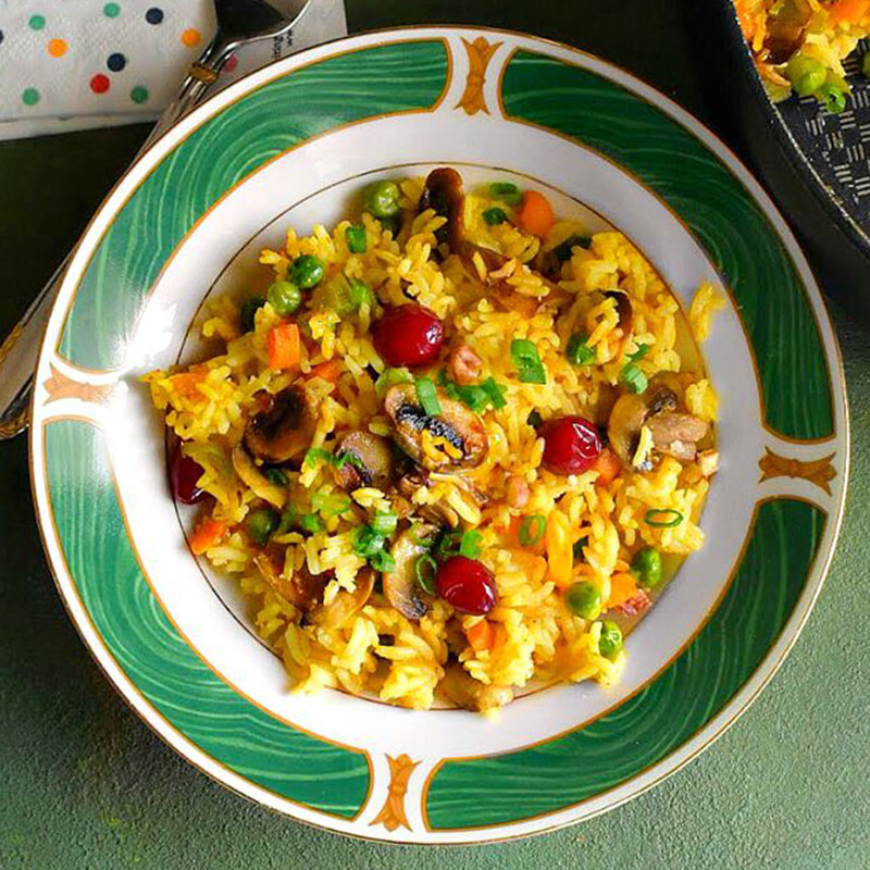 Close up view of easy one-pot mushroom rice pilaf in a white and green bowl.