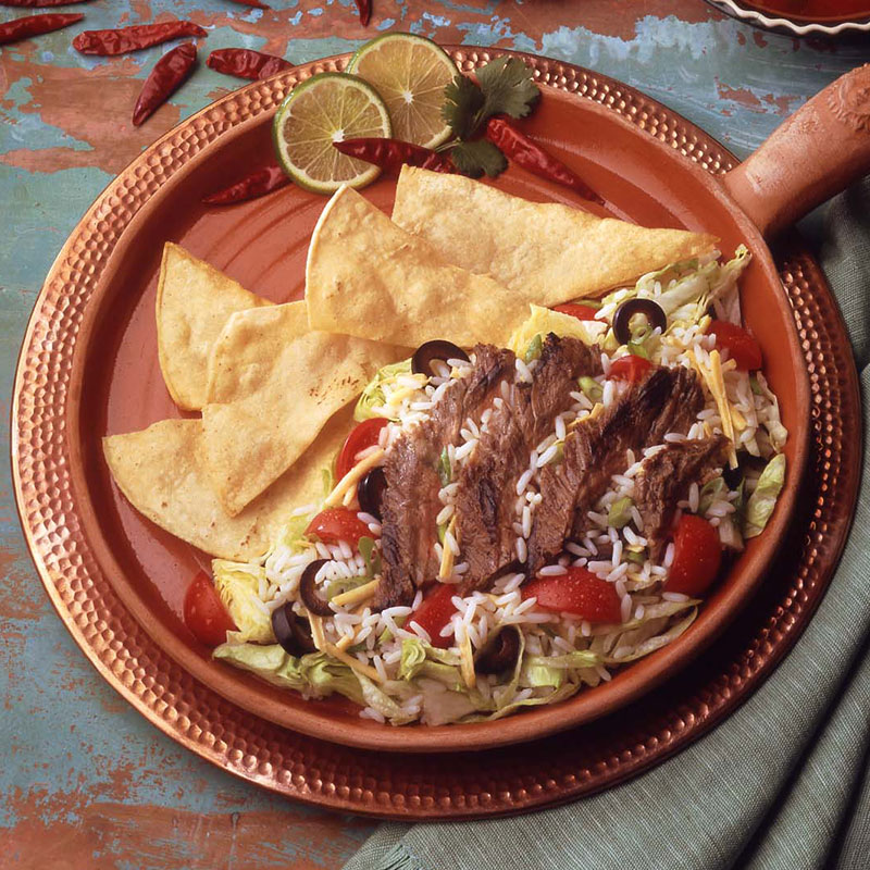 Overhead view of fajita rice salad on a terracotta plate.