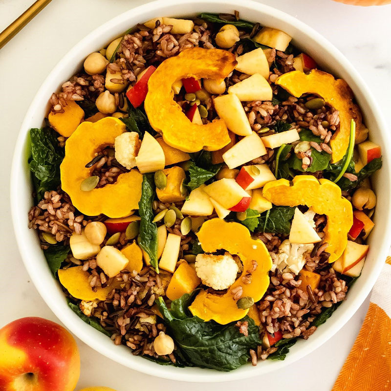 Overhead shot of a fall colored Wild Rice salad topped with squash, pumpkin, and apple pieces.