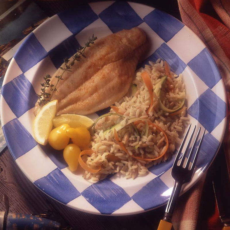 Overhead view of fast dish catfish and rice on a checkered plate.