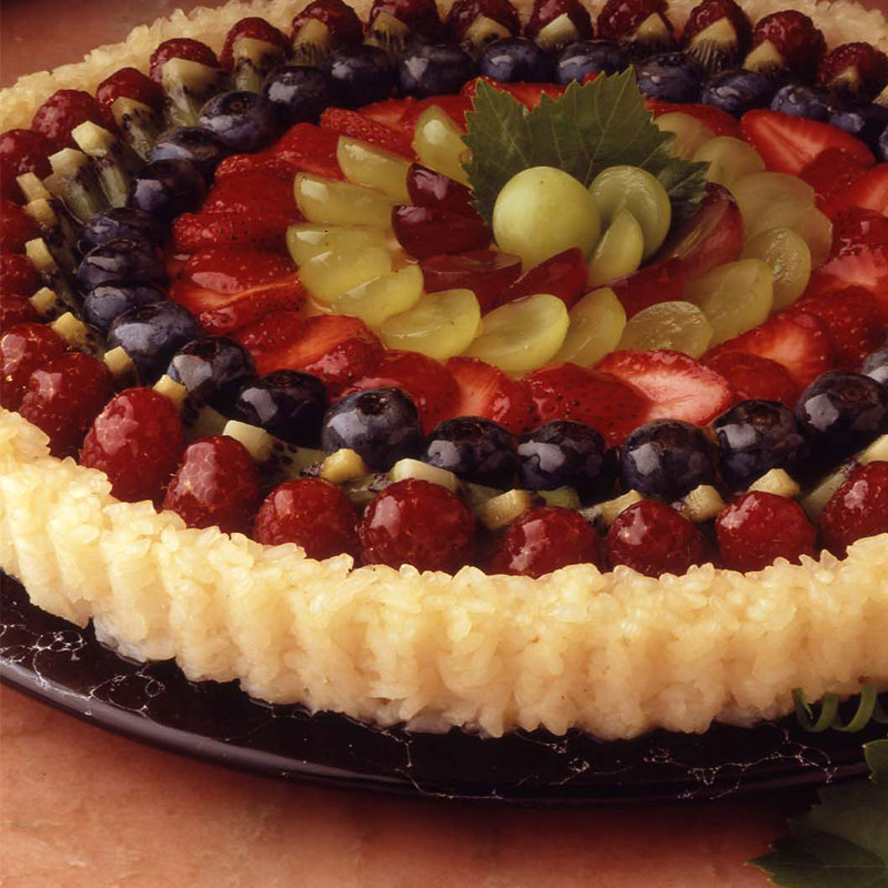 Side view of fresh fruit tart with rice crust on a platter.