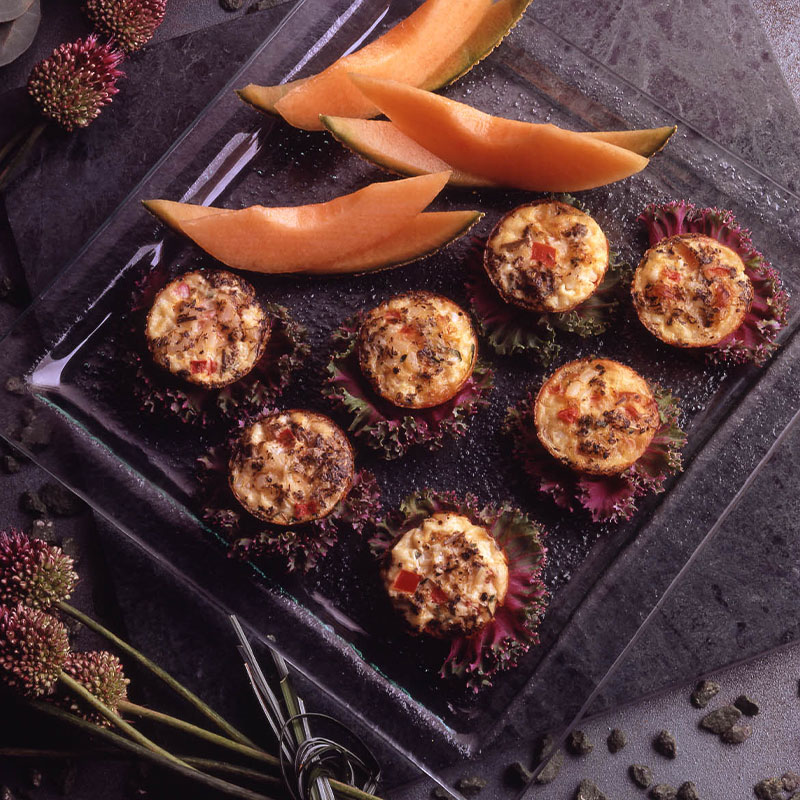 Overhead shot of seven Frittata Bites along with cantaloupe slices. 