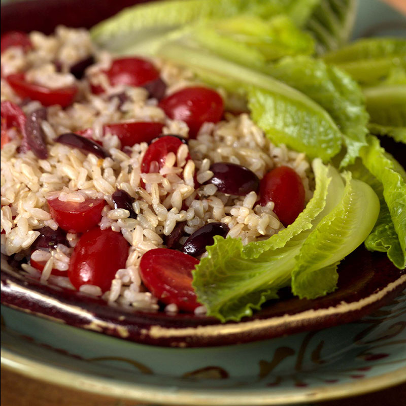 Greek Rice topped with lettuce leaves in a green dish.