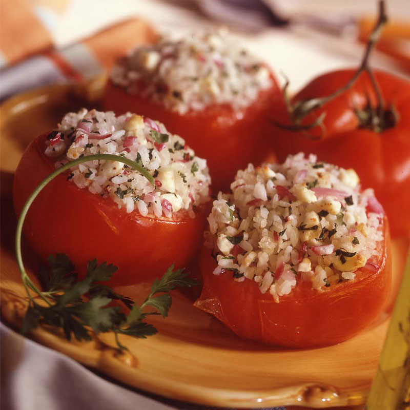 Close up view of Greek rice stuffed tomatoes on a yellow plate.