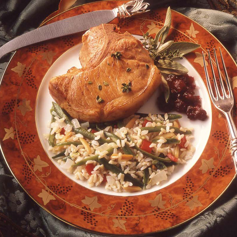 Overhead view of green bean almond rice on a plate with grilled meat.