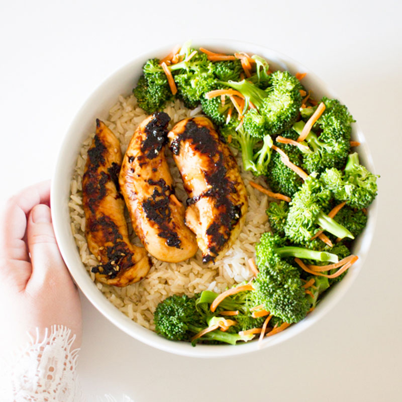 Overhead view of grilled chicken and veggie rice bowl.