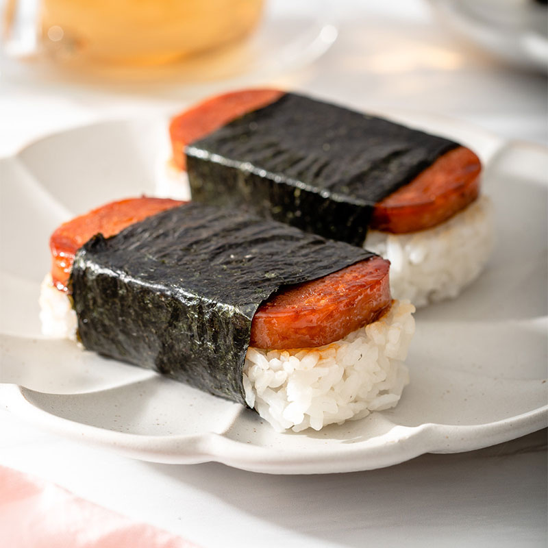 Side angle of Hawaiian Spam Musubi on a white plate.