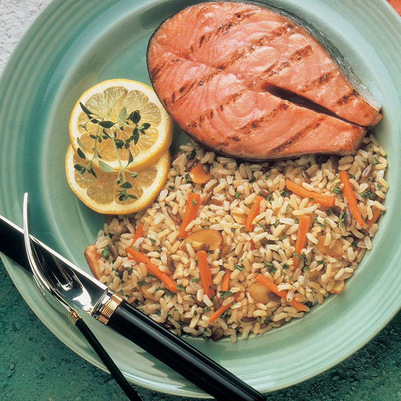 Overhead view of health nut brown rice with grilled meat on a blue plate.