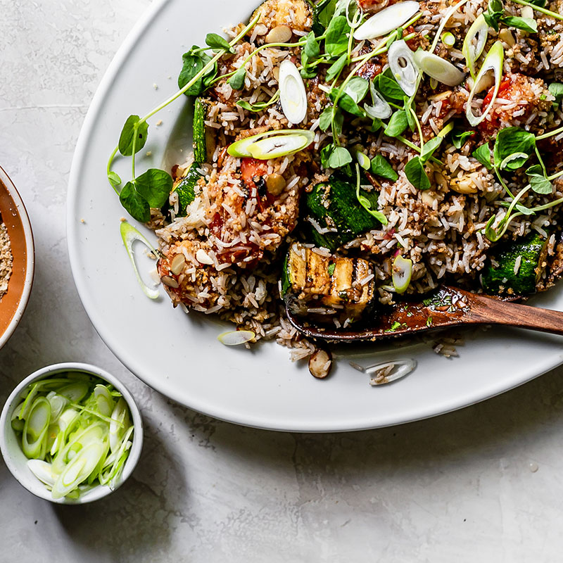 Overhead view of herby rice salad with vegetables on a white platter.