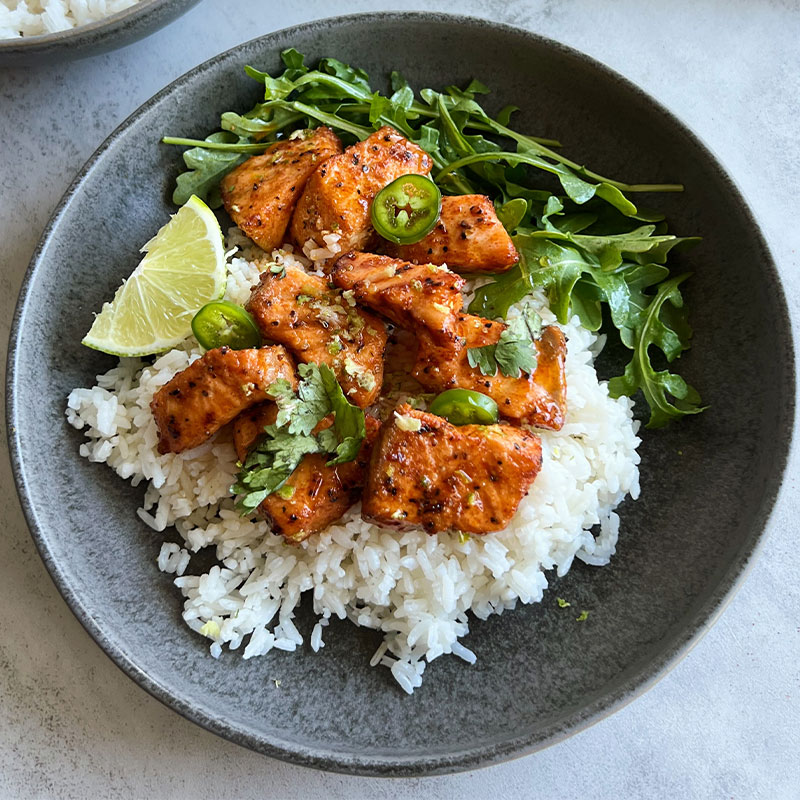 A bowl of Hot Honey Salmon Bites over rice.