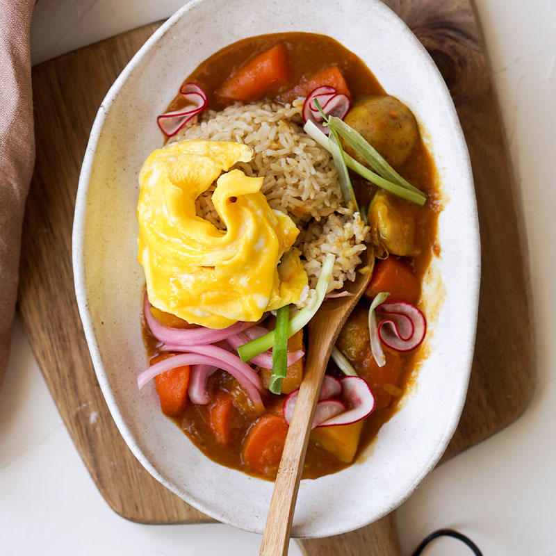 Japanese Brown Rice Curry Overhead shot of Japanese Brown Rice Curry in a white dish topped with an egg.
