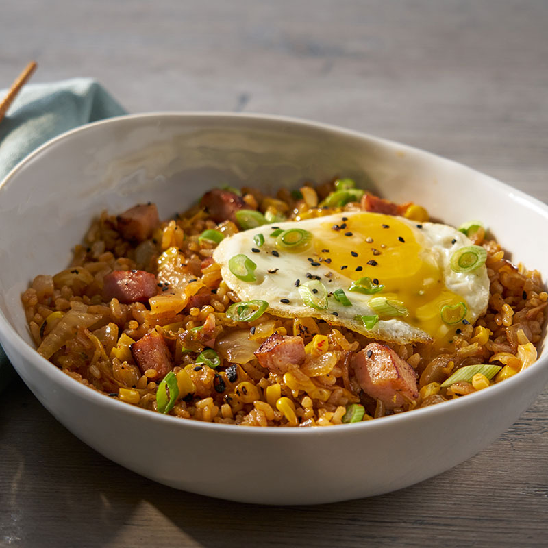 Side view of Korean spam fried rice in a white bowl with a fried egg on top.
