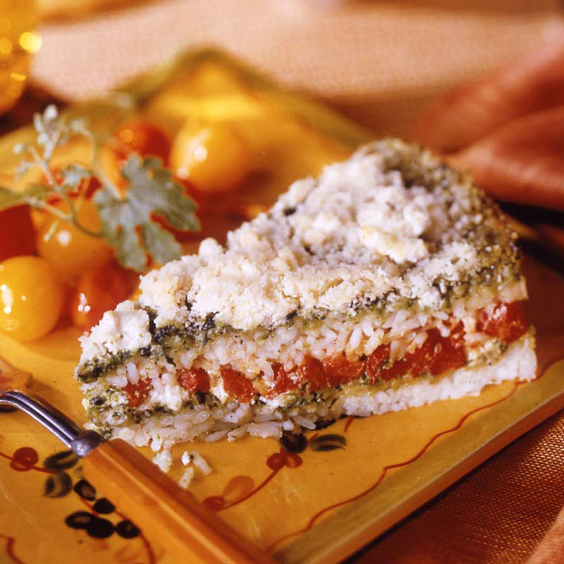 Side view of layered rice pesto and pepper bake on a yellow plate.