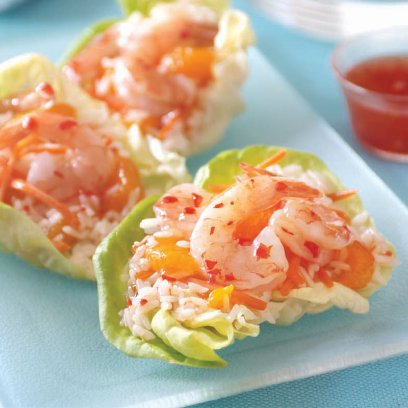 Close up view of mandarin orange rice and shrimp lettuce wraps on a clear serving dish.