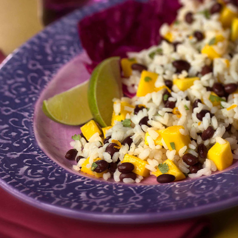 Mango Tango Rice Salad displayed in a purple dish with lime wedges.