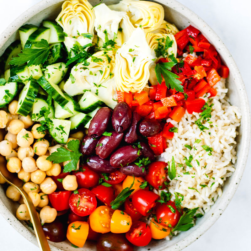 Overhead shot of a colorful Mediterranean Brown Rice Salad in a large bowl.