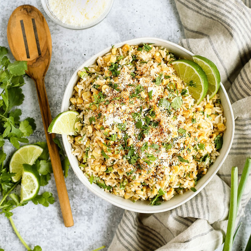 Mexican Street Corn and Rice Bowls Overhead shot of a Mexican Street Corn and Rice Bowl topped with lime wedges.