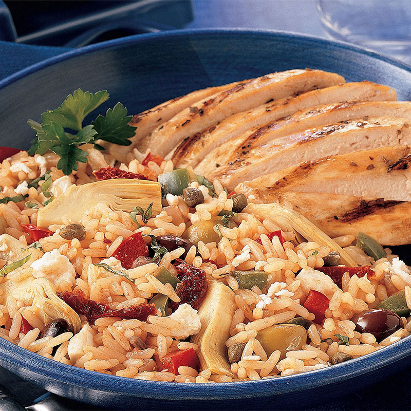 Side view of Mykonos Greek rice on a blue plate with grilled chicken.