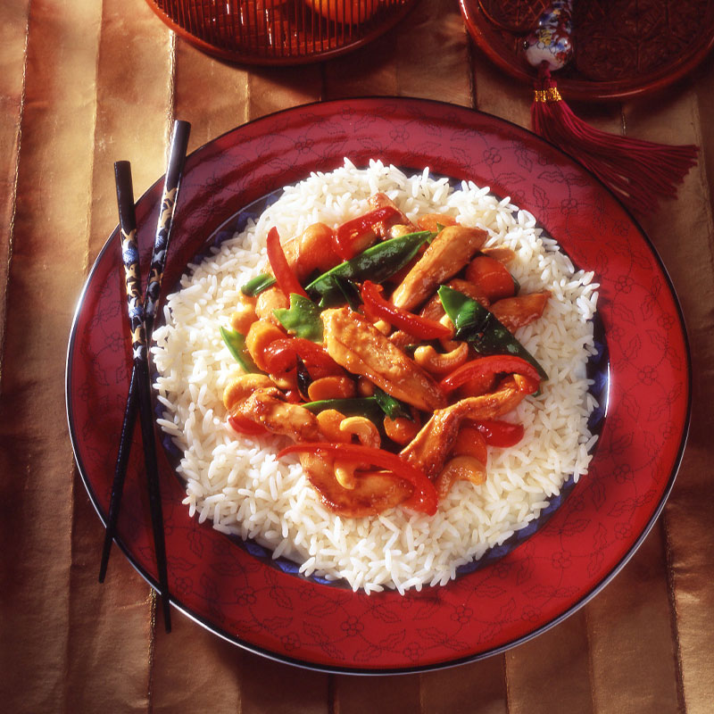 Overhead shot of Orange Chicken Stir-Fry on a red plate with chopsticks to the side.