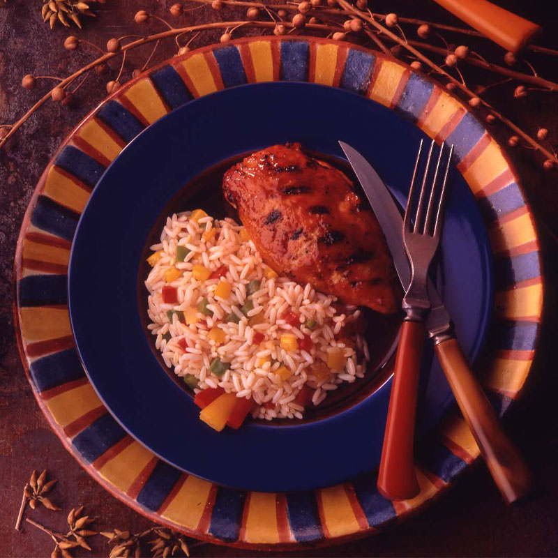 A serving of Pepper Rice accompanies a chicken breast on a blue plate.