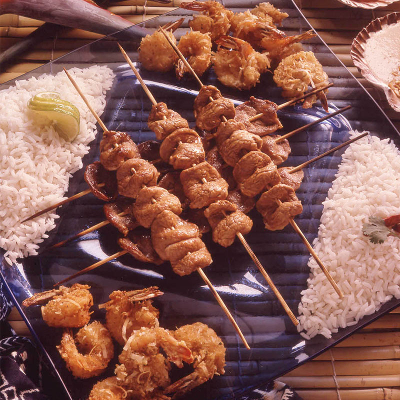 Overhead view of pork sate with rice and peanut sauce on a platter.