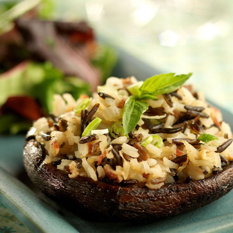 Portobello Mushrooms Stuffed with California Wild Rice Side shot of one Fresh Herbed Portobello mushroom stuffed with brown and wild rice.