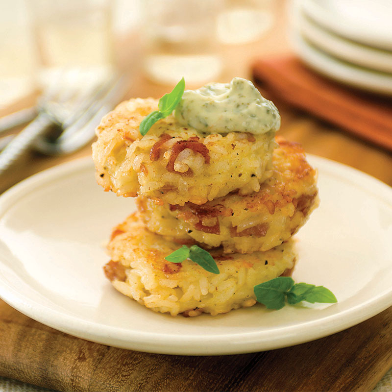 Side view of prosciutto and asiago rice cakes with pesto aioli on a white plate.