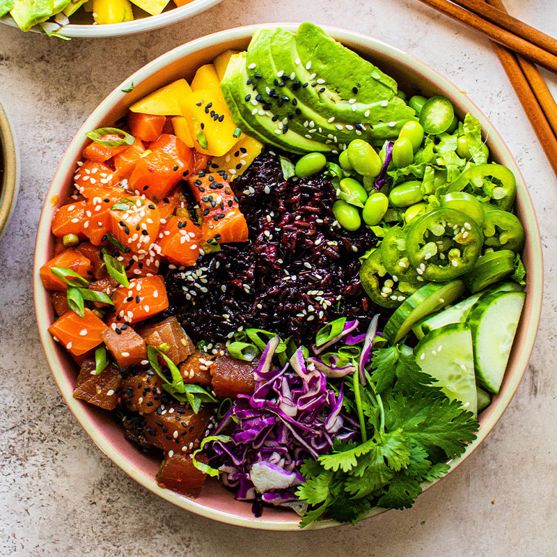 Overhead shot of a colorful poke bowl with purple rice.