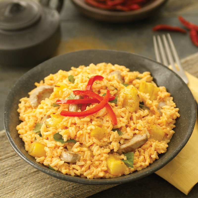 Overhead shot of Red Curry Coconut Rice with Pork in a bowl topped with red pepper slices.