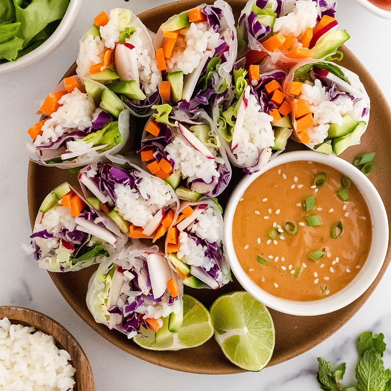 Overhead view of a platter of Rice & Veggie Spring Rolls with Thai Peanut Dipping Sauce.