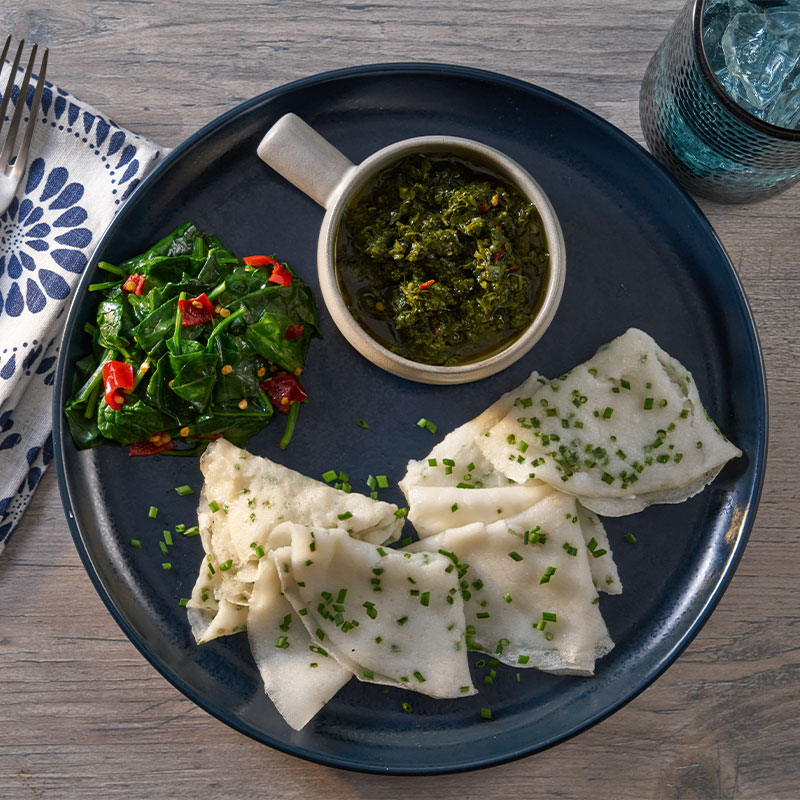 Overhead shot of six Rice Crepes with a side of spinach and a green dipping sauce