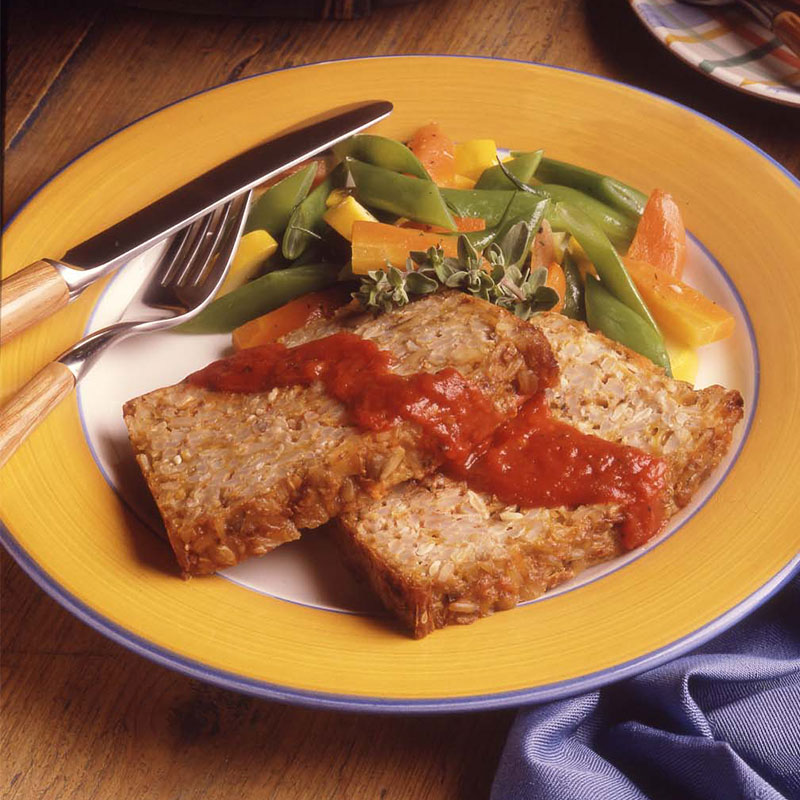 Overhead view of rice-nut loaf on a plate with vegetable medley.  