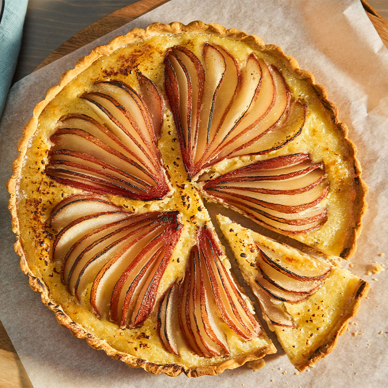 Overhead shot of a full Rice Pudding Pear Tart with one slice cut.