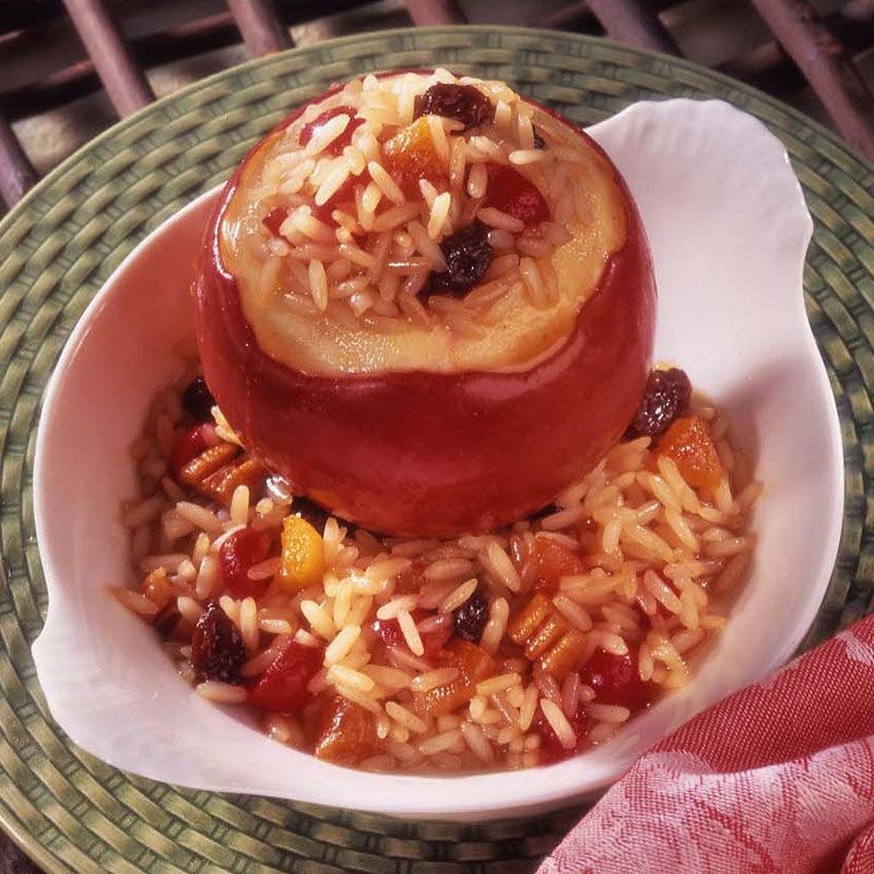 Overhead view of a rice stuffed baked apple on a white plate.