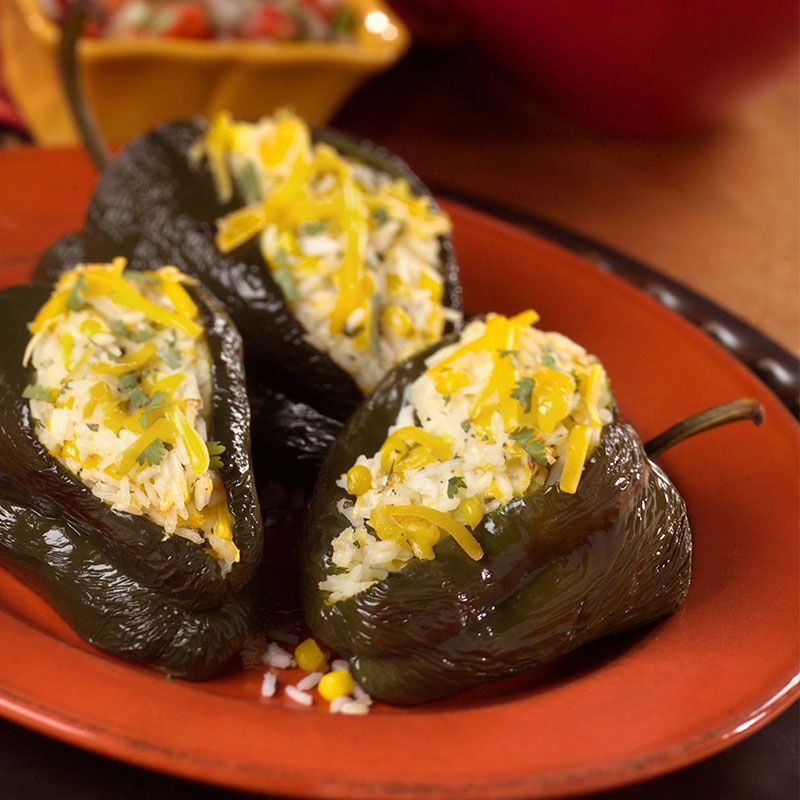 Rio Bravo Rice-Stuffed Poblanos Side view of Rio bravo rice-stuffed poblanos on a red plate.
