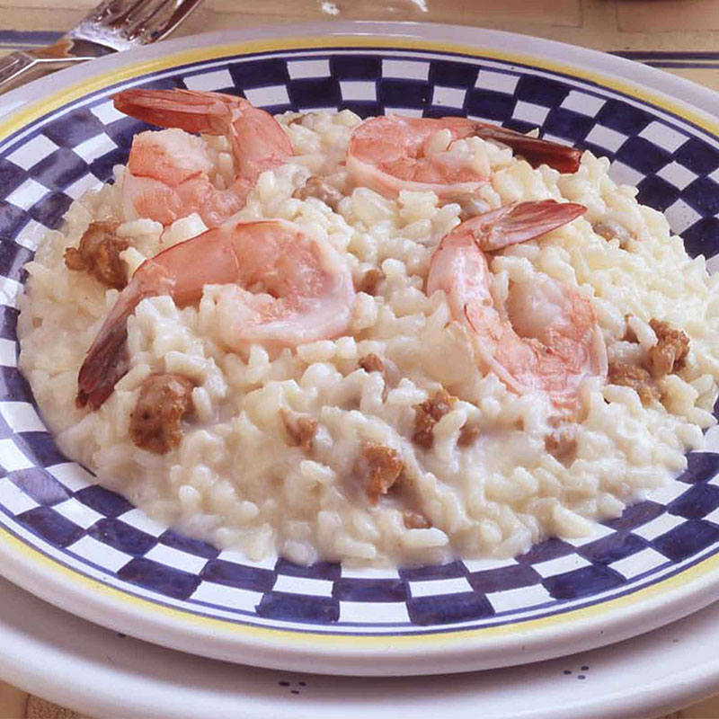 Close up of risotto with sausage and shrimp on a checkered pattern plate.
