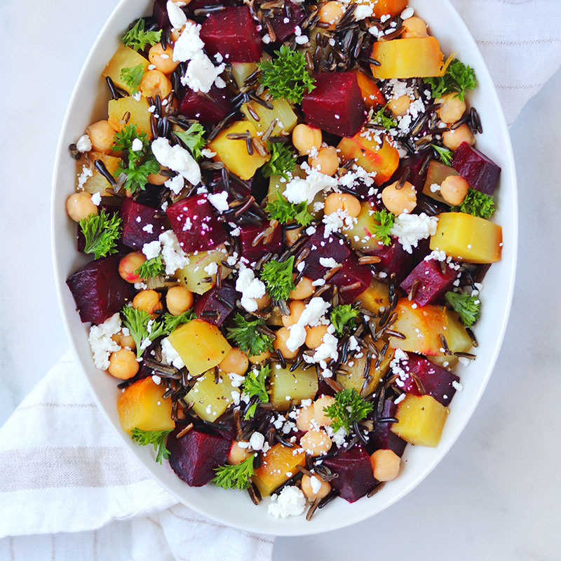 Overhead view of roasted beet and goat cheese wild rice salad in a white serving dish.