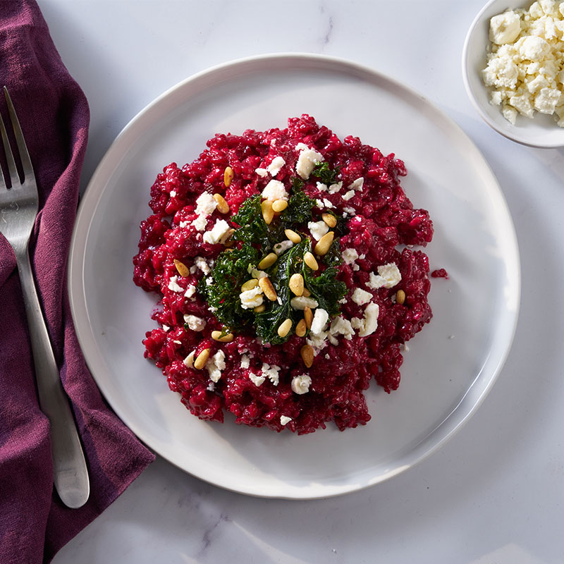 Overhead view of roasted beet risotto on a white plate.