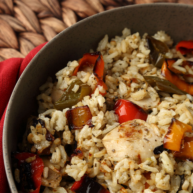A zoomed in shot of white rice, chicken, and roasted peppers in a bowl.