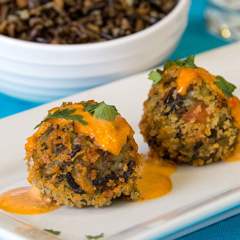 Close up view of Saigon style wild rice and salmon fritters on a white plate garnished with red curry mayonnaise.