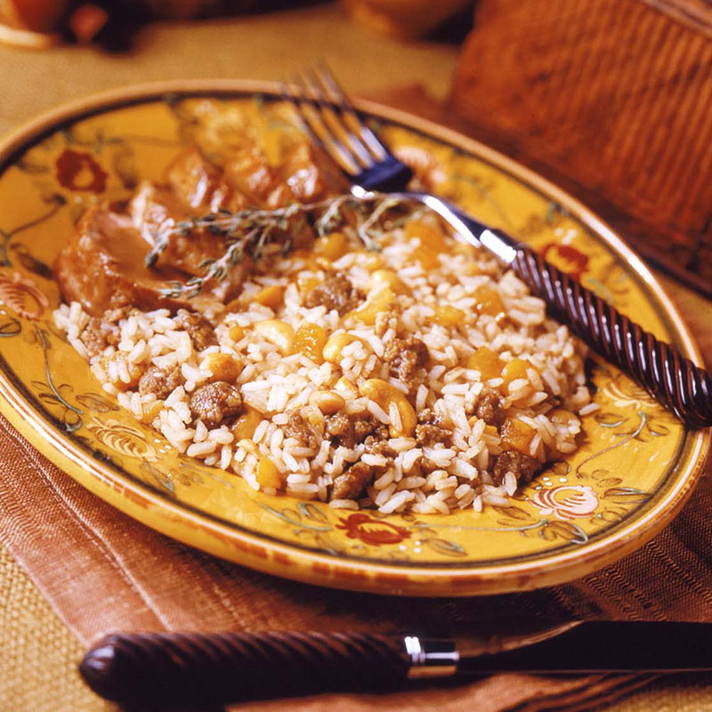 Side view of sausage and apricot balsamic rice on a yellow plate.