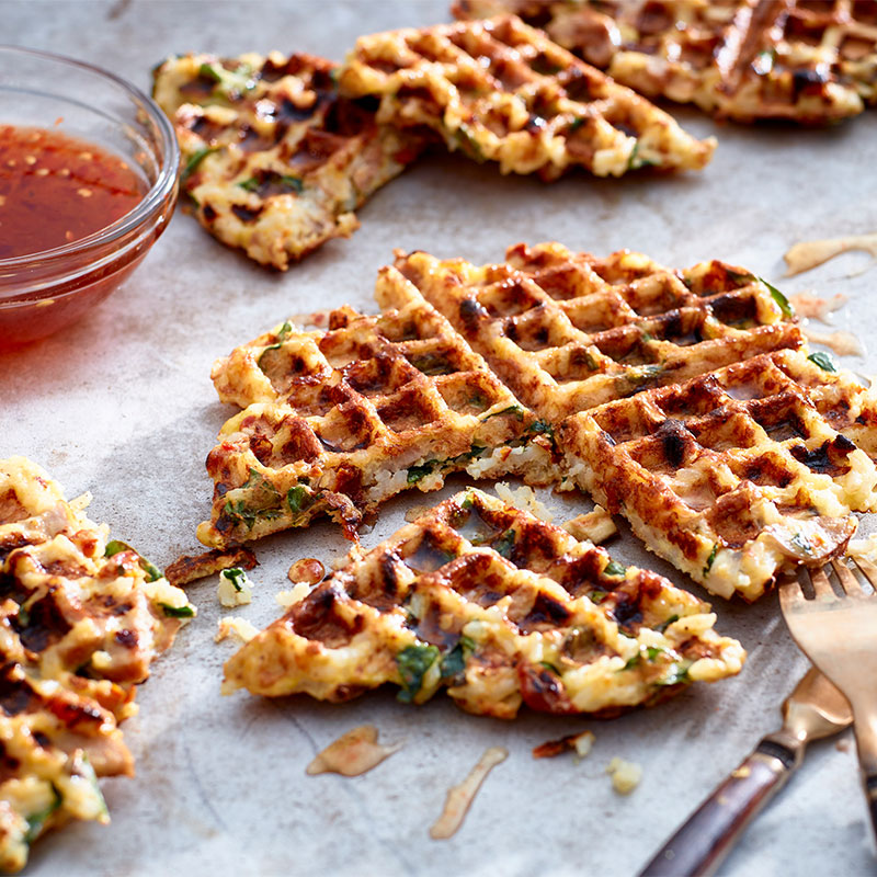 Savory Rice Waffles Close up image of a Savory Rice Waffle with additional waffles in the background.