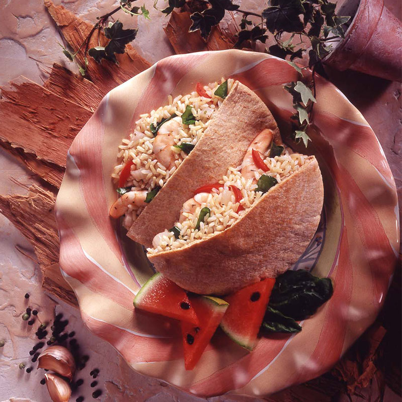 Overhead image of two open pitas bursting with shrimp & rice mixture on a plate.