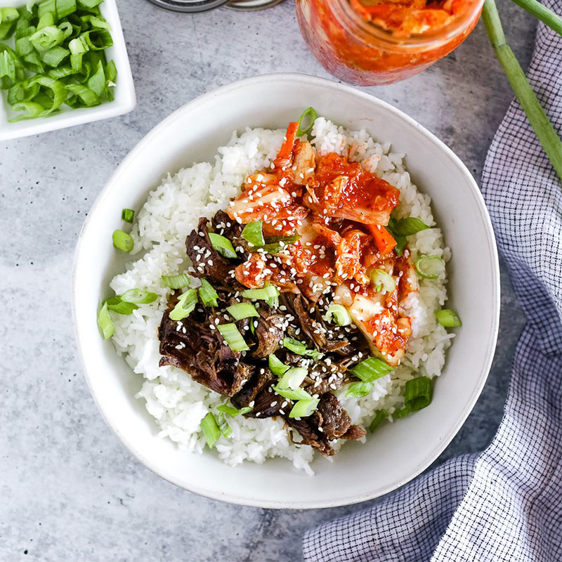Slow Cooker Korean Beef and Rice Bowls Overhead view of a Slow Cooker Korean Beef and Rice Bowl topped with Korean toppings.