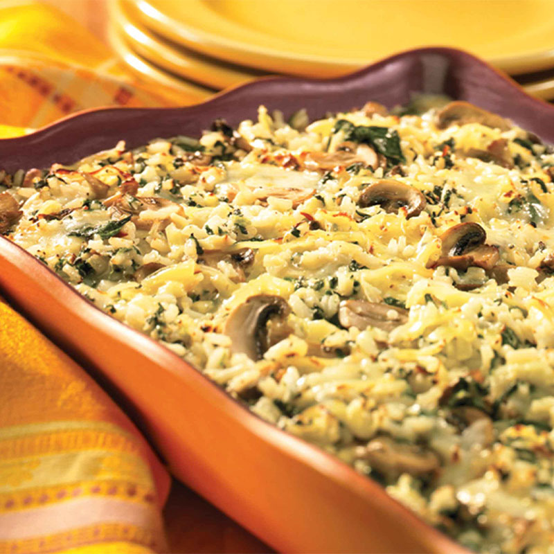A side view of a orange serving platter filled with Smoked Gouda and Spinach Rice Casserole.  